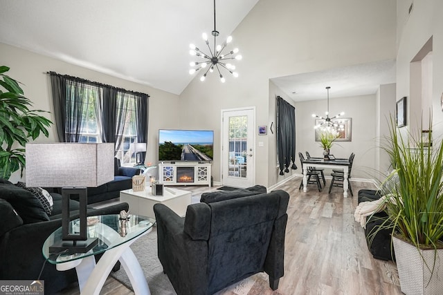 living room featuring a chandelier, light hardwood / wood-style flooring, a textured ceiling, and high vaulted ceiling