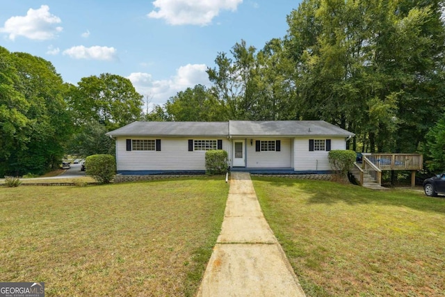 ranch-style home featuring a deck and a front lawn