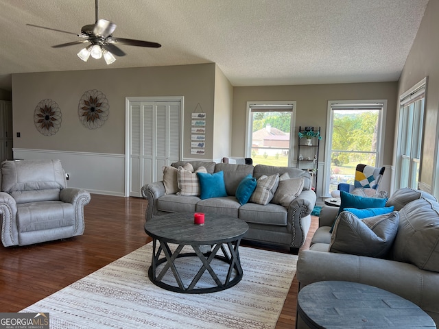 living room featuring vaulted ceiling, ceiling fan, dark wood-type flooring, and a textured ceiling