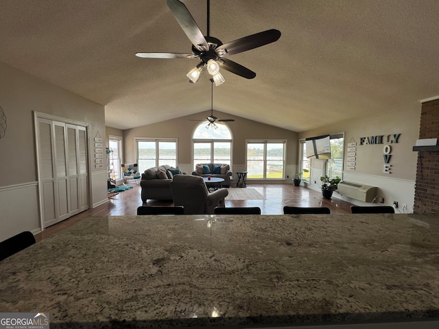 living room featuring a textured ceiling, ceiling fan, wood-type flooring, and lofted ceiling