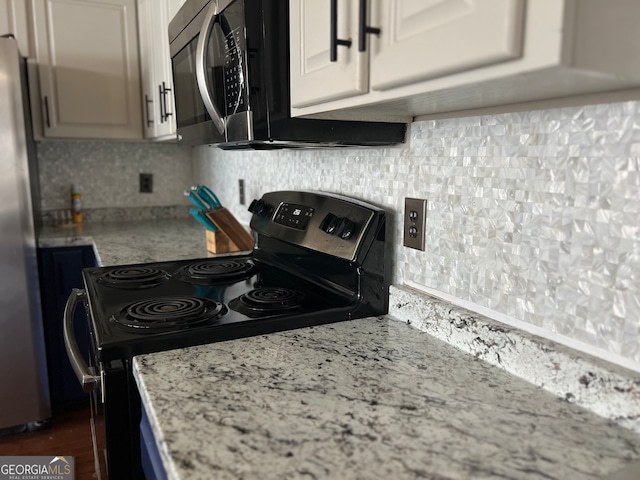 kitchen with light stone countertops, backsplash, stainless steel appliances, and white cabinetry