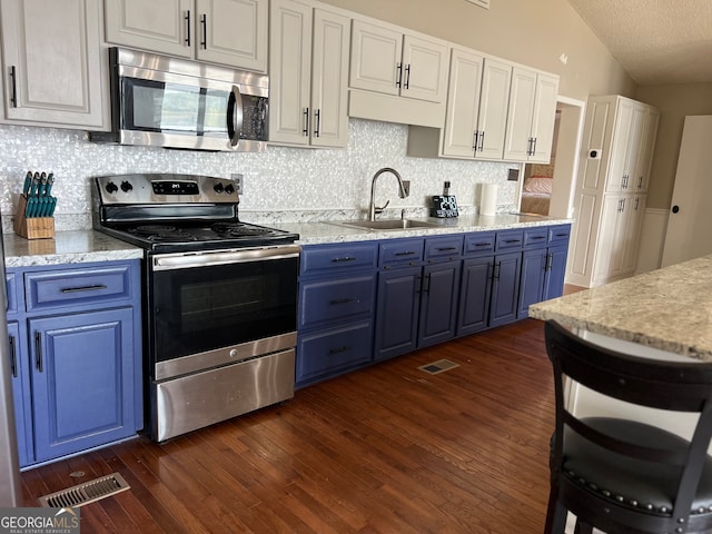 kitchen featuring white cabinetry, dark hardwood / wood-style flooring, lofted ceiling, and stainless steel appliances