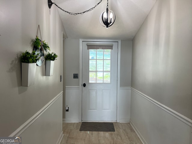 doorway with light wood-type flooring and a textured ceiling