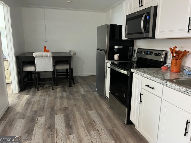 kitchen featuring appliances with stainless steel finishes, white cabinetry, ornamental molding, and dark wood-type flooring