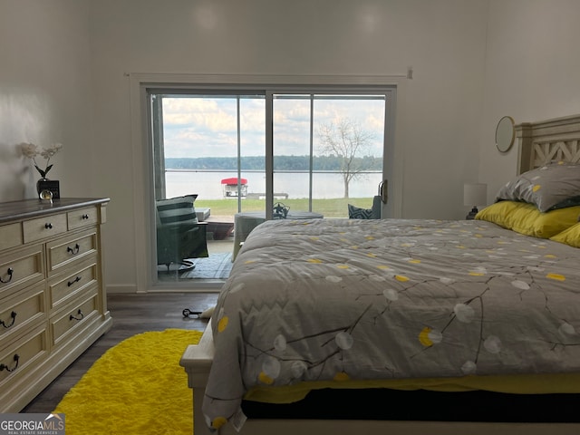 bedroom featuring access to exterior, a water view, and dark wood-type flooring