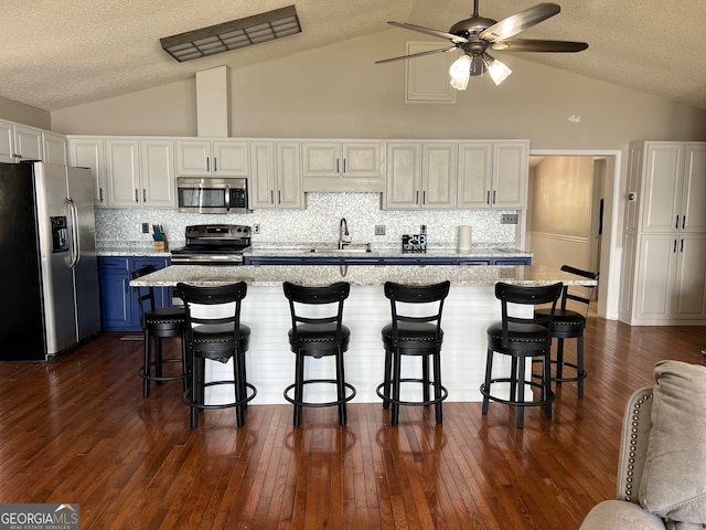 kitchen with a kitchen breakfast bar, white cabinetry, dark hardwood / wood-style flooring, and stainless steel appliances