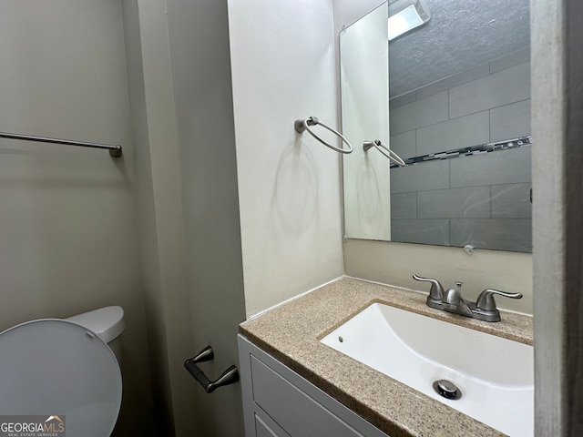 bathroom featuring a textured ceiling, vanity, and toilet