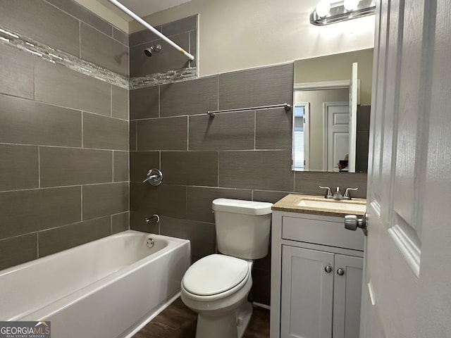 full bathroom featuring wood-type flooring, vanity, tiled shower / bath combo, and toilet