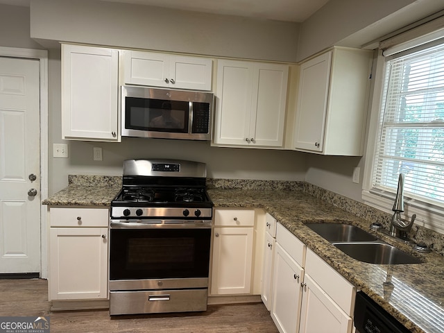 kitchen featuring appliances with stainless steel finishes, white cabinetry, sink, and dark wood-type flooring