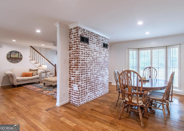 dining room featuring brick wall and hardwood / wood-style flooring