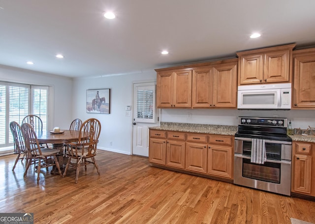 kitchen featuring light stone counters, light hardwood / wood-style flooring, and double oven range