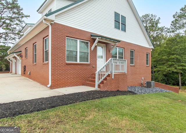 view of front of property with central AC unit, a garage, and a front lawn