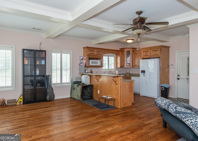 kitchen featuring a breakfast bar area, kitchen peninsula, crown molding, white appliances, and dark hardwood / wood-style flooring