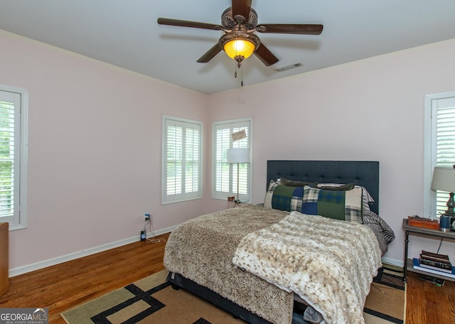 bedroom featuring multiple windows, ceiling fan, and hardwood / wood-style flooring