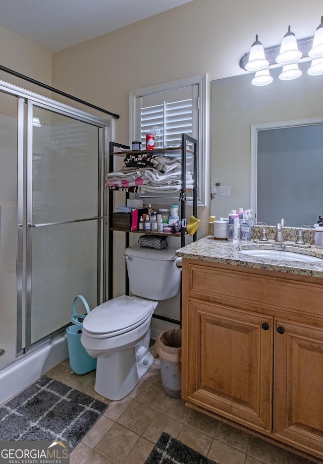 bathroom with vanity, a shower with shower door, toilet, and tile patterned flooring