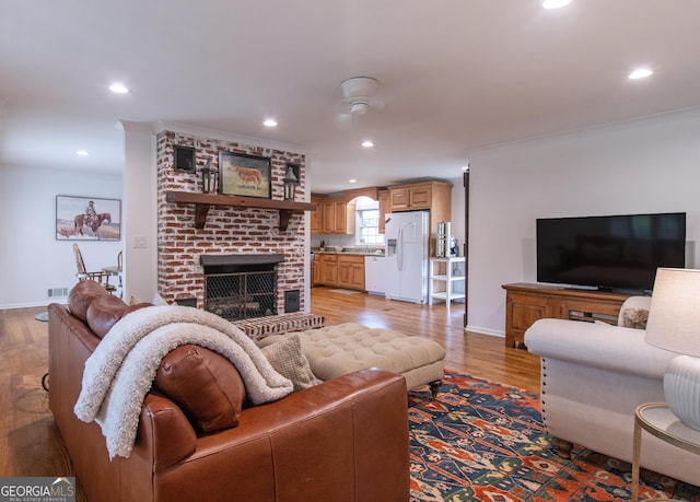 living room featuring light wood-type flooring, a fireplace, and ornamental molding