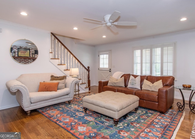 living room with wood-type flooring, ornamental molding, and ceiling fan