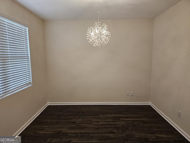 empty room featuring baseboards, a chandelier, and dark wood-style flooring