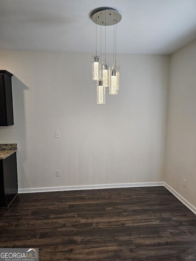 unfurnished dining area featuring baseboards and dark wood finished floors