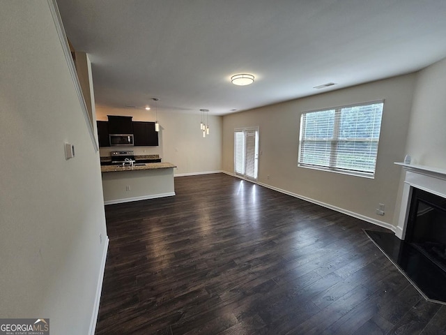 unfurnished living room featuring visible vents, a fireplace, baseboards, and dark wood-style flooring