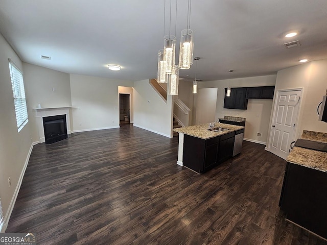 kitchen featuring a sink, open floor plan, dark wood finished floors, baseboards, and light stone countertops