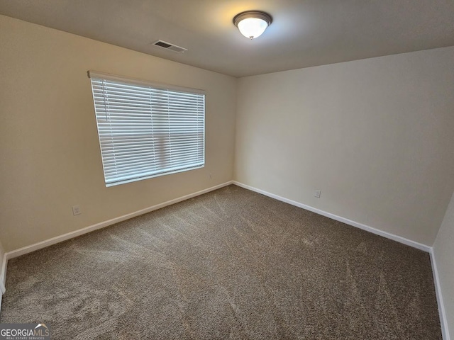 unfurnished room with baseboards, visible vents, and dark colored carpet