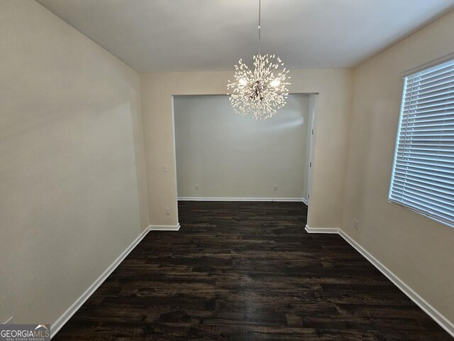 unfurnished dining area featuring dark wood finished floors, a notable chandelier, and baseboards