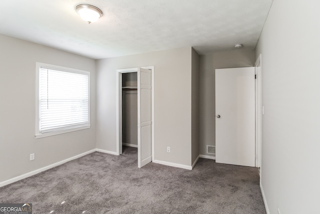 unfurnished bedroom with a textured ceiling, a closet, and carpet