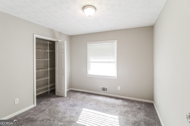 unfurnished bedroom featuring a closet, carpet floors, and a textured ceiling