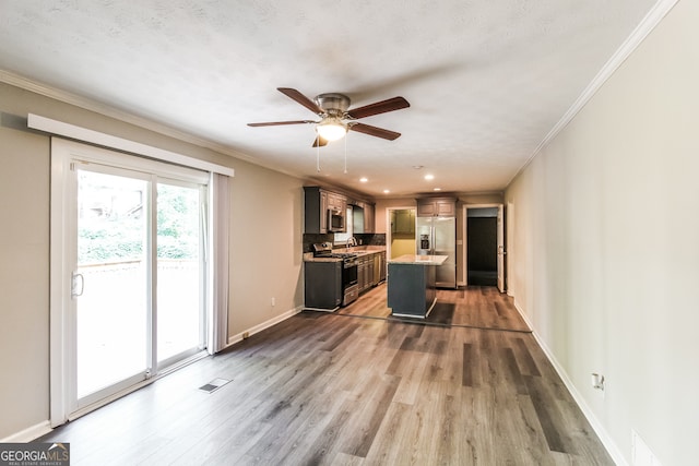 kitchen featuring ceiling fan, ornamental molding, a kitchen island, stainless steel appliances, and dark hardwood / wood-style flooring