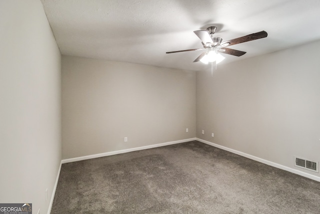 empty room featuring ceiling fan and dark colored carpet