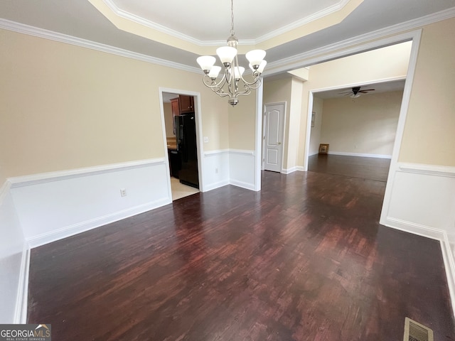 empty room with ceiling fan with notable chandelier, a tray ceiling, crown molding, and dark hardwood / wood-style flooring