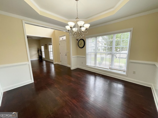 unfurnished dining area featuring crown molding, a tray ceiling, dark hardwood / wood-style floors, and a chandelier