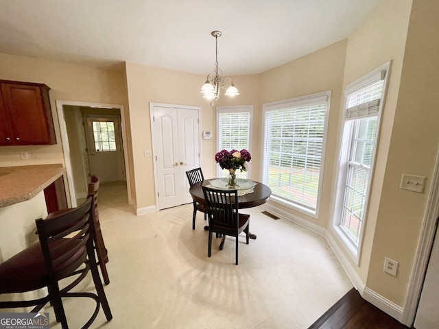 dining area with a chandelier and light colored carpet