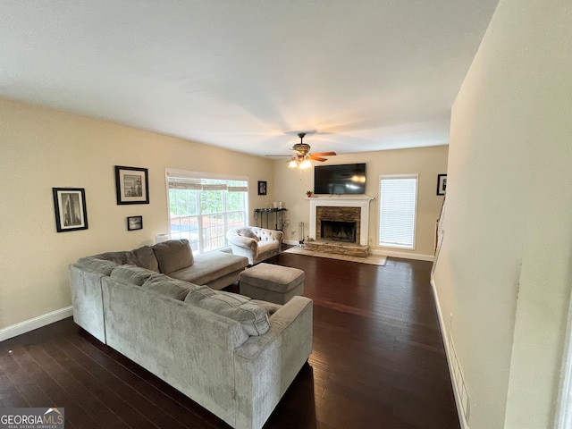 living room with a stone fireplace, ceiling fan, and dark hardwood / wood-style flooring