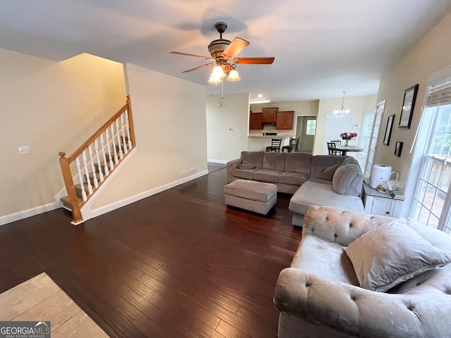 living room with ceiling fan with notable chandelier and dark hardwood / wood-style flooring