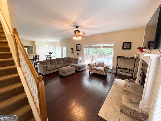 living room with ceiling fan, dark hardwood / wood-style floors, and a stone fireplace