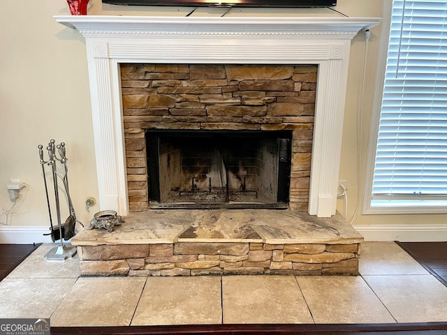 interior details with a stone fireplace and tile patterned floors