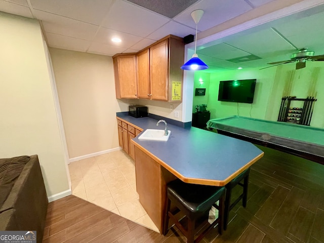 kitchen with hanging light fixtures, a breakfast bar area, light wood-type flooring, ceiling fan, and sink