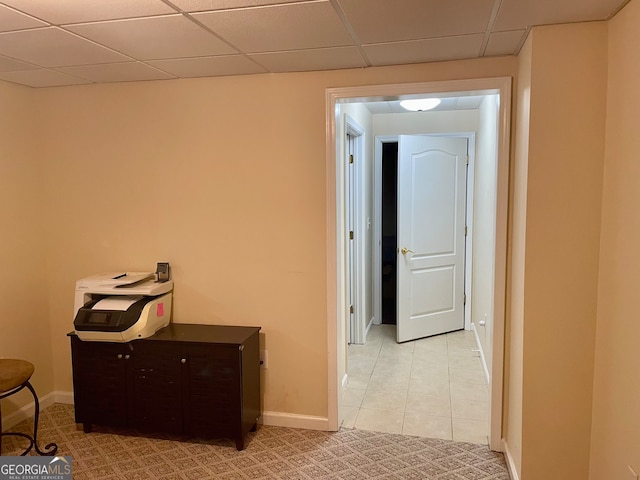 corridor with light tile patterned flooring and a paneled ceiling