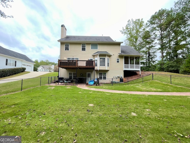 back of house featuring a lawn, a wooden deck, and a sunroom