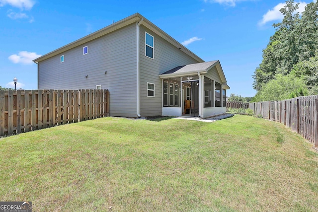 rear view of house featuring a yard and a sunroom