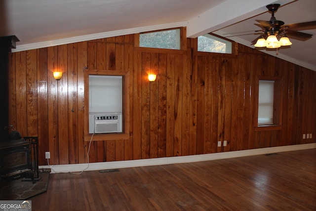 unfurnished living room featuring a wood stove, ceiling fan, wood walls, crown molding, and hardwood / wood-style flooring