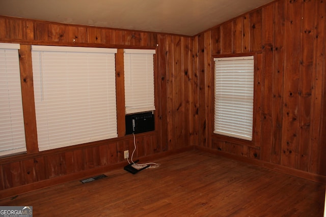 unfurnished living room featuring hardwood / wood-style flooring and wood walls