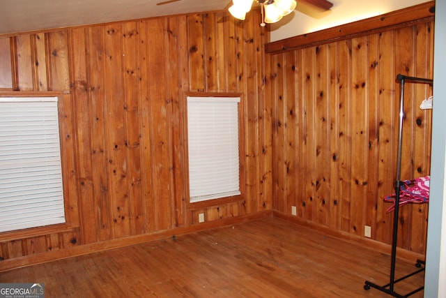 spare room featuring hardwood / wood-style flooring, ceiling fan, and wooden walls