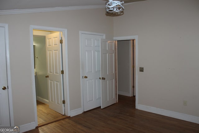 unfurnished bedroom featuring crown molding, lofted ceiling, and dark wood-type flooring