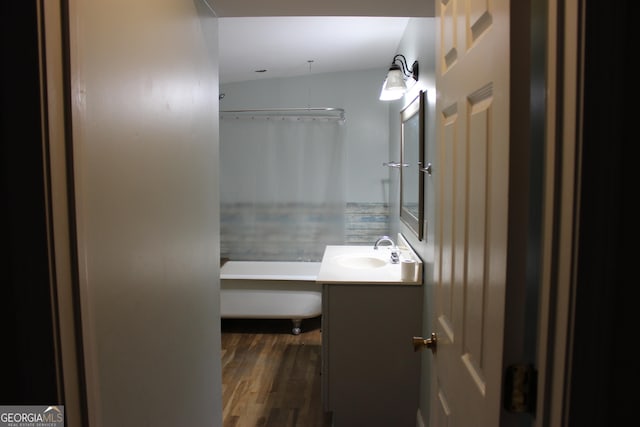 bathroom featuring wood-type flooring, vanity, and lofted ceiling