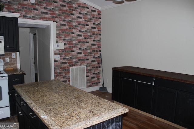 kitchen with brick wall, dark hardwood / wood-style floors, white range with electric stovetop, a kitchen island, and ornamental molding