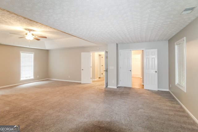 unfurnished bedroom featuring a textured ceiling, ceiling fan, and light colored carpet