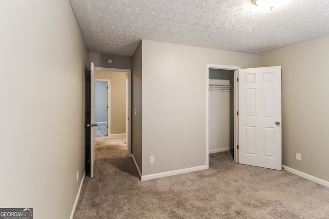 unfurnished bedroom featuring a textured ceiling, light carpet, and a closet